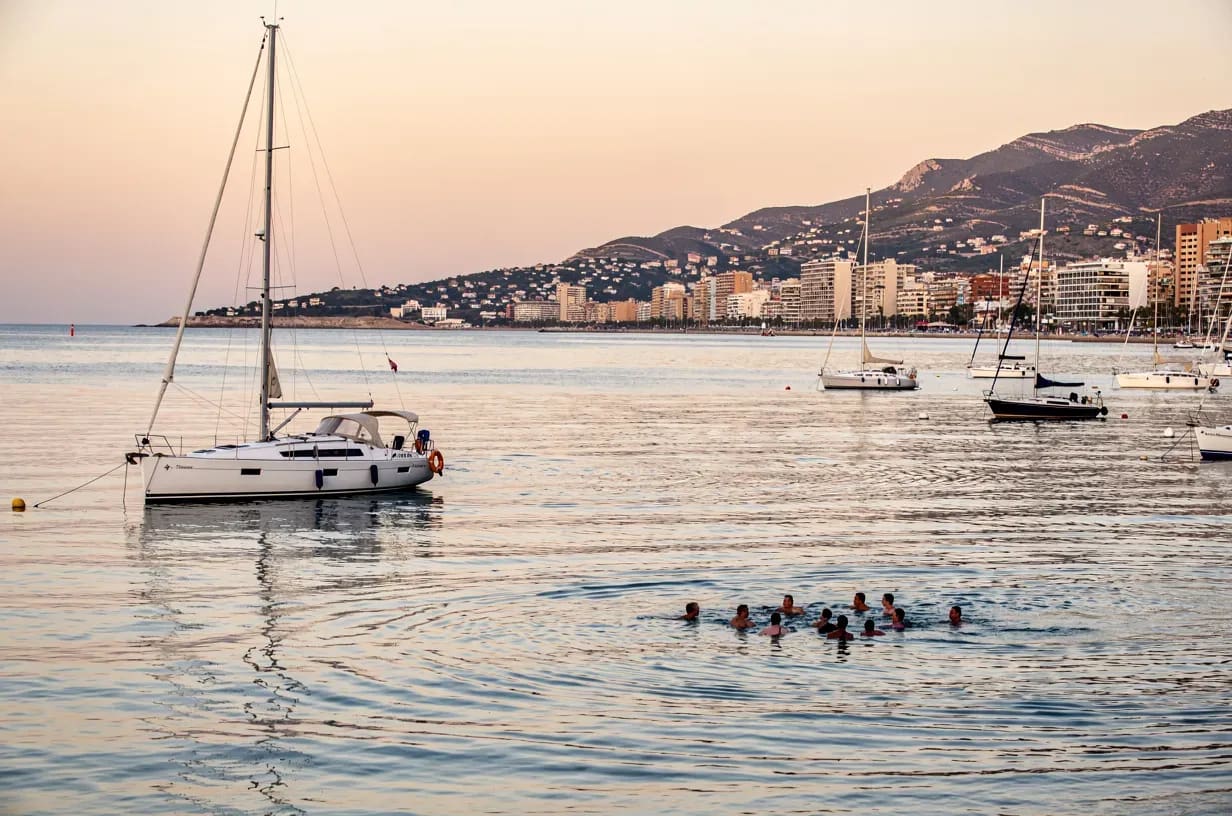 Velero fondeado en la bahia de Alicante con separacion prudente de bañistas y otros barcos