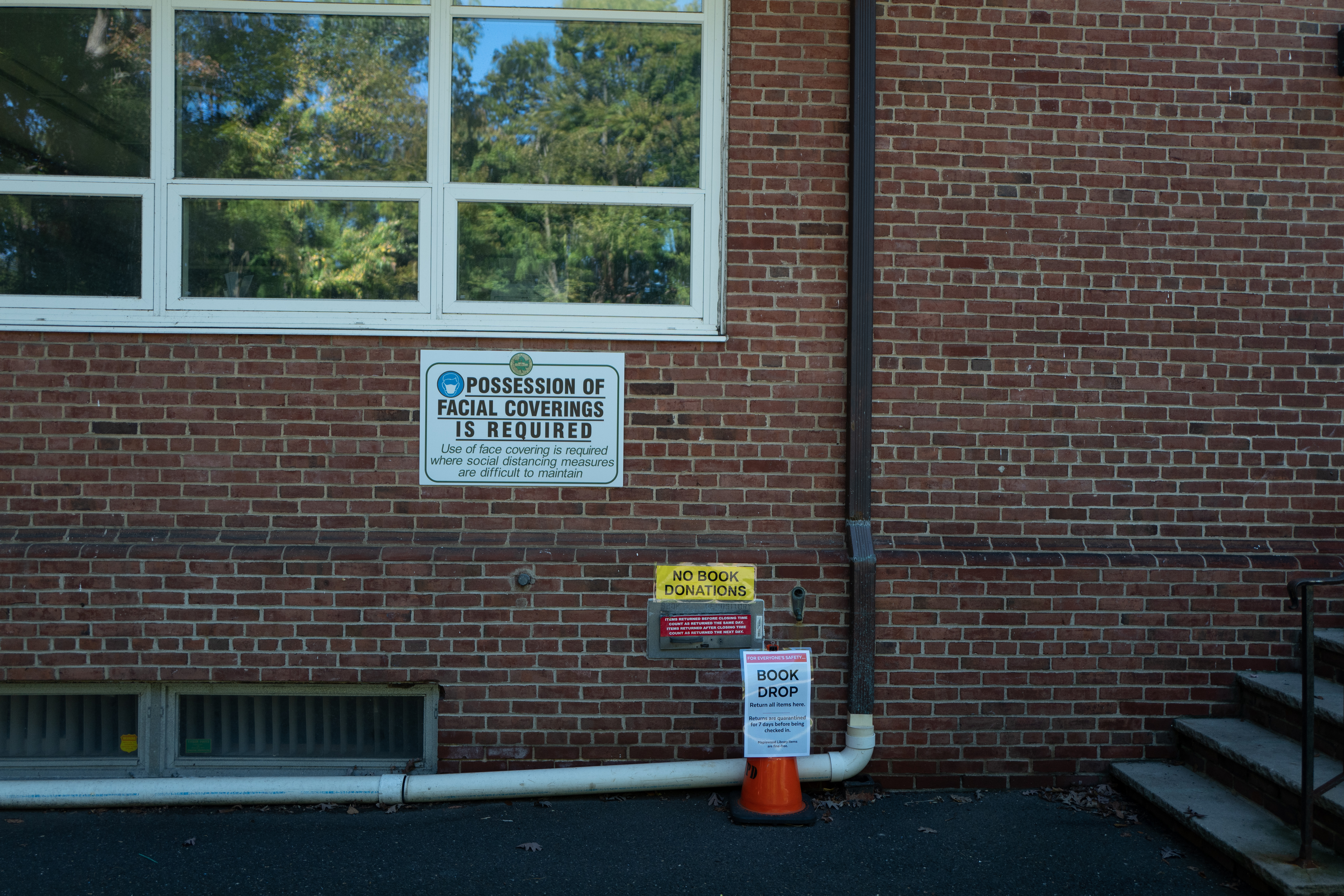 Covid mask mandate sign at Maplewood, NJ public library Brick wall of a building with a COVID-19 mask mandate sign