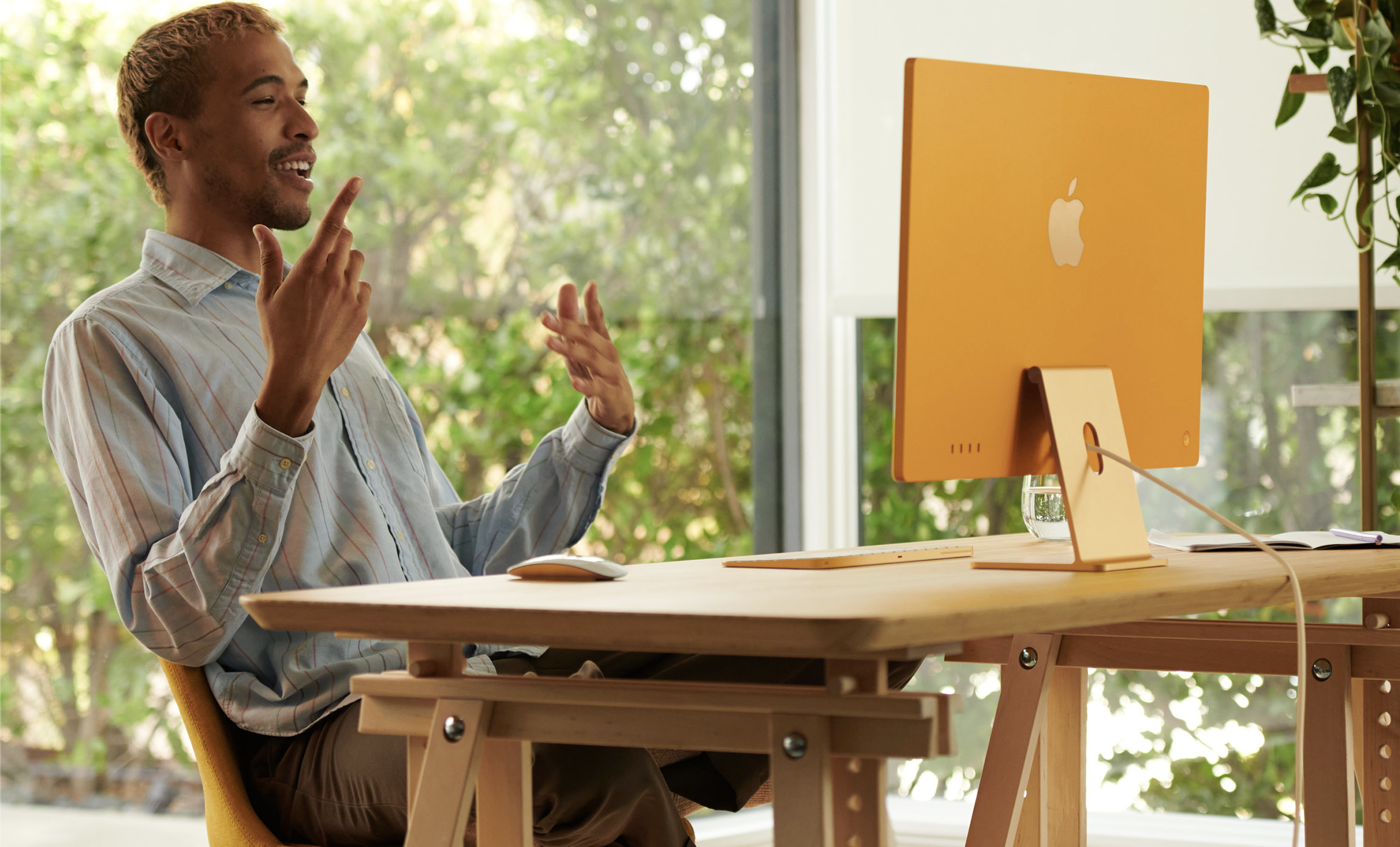 An excited person making hand gestures at a yellow iMac computer
