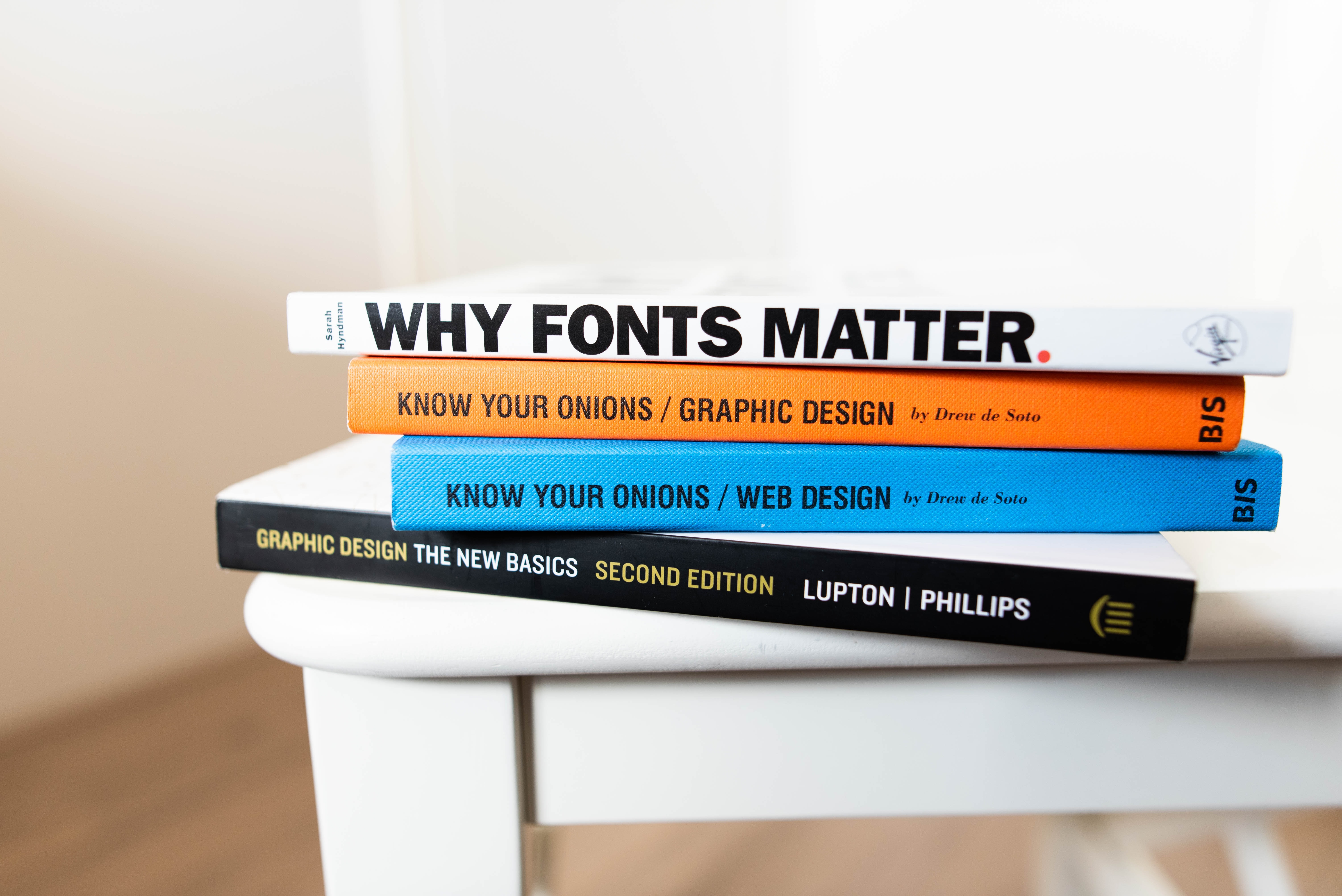 Stack of books about design, including one titled 'Why Fonts Matter'