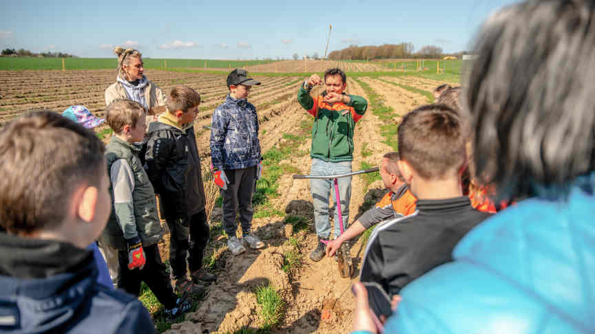 Ein Mann zeigt einer Gruppe von Kindern einen Setzling