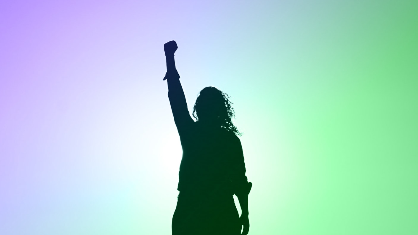 Woman holding up her fist against a purple and green sky