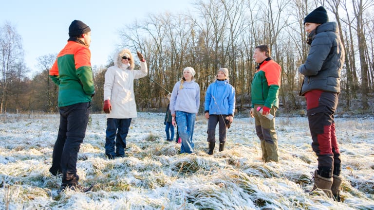 Group standing on a snow-white meadow with young trees.