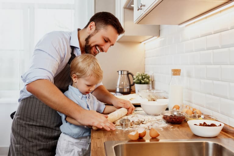 Lachender Vater, welcher mit seinem Sohn Kekse macht.