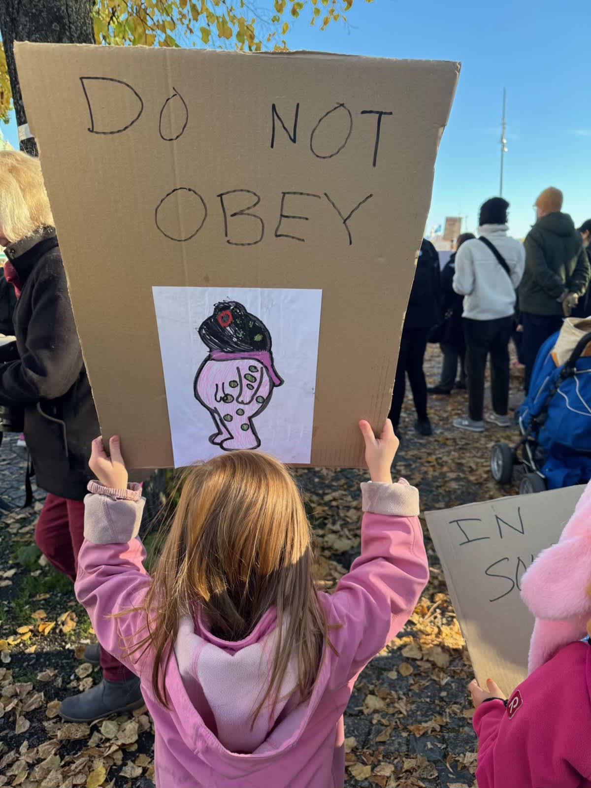 A young protester holds up a sign that reads "do not obey".