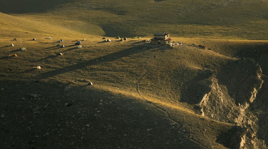 Plusieurs tentes installées autour d'un chalet refuge en montagne