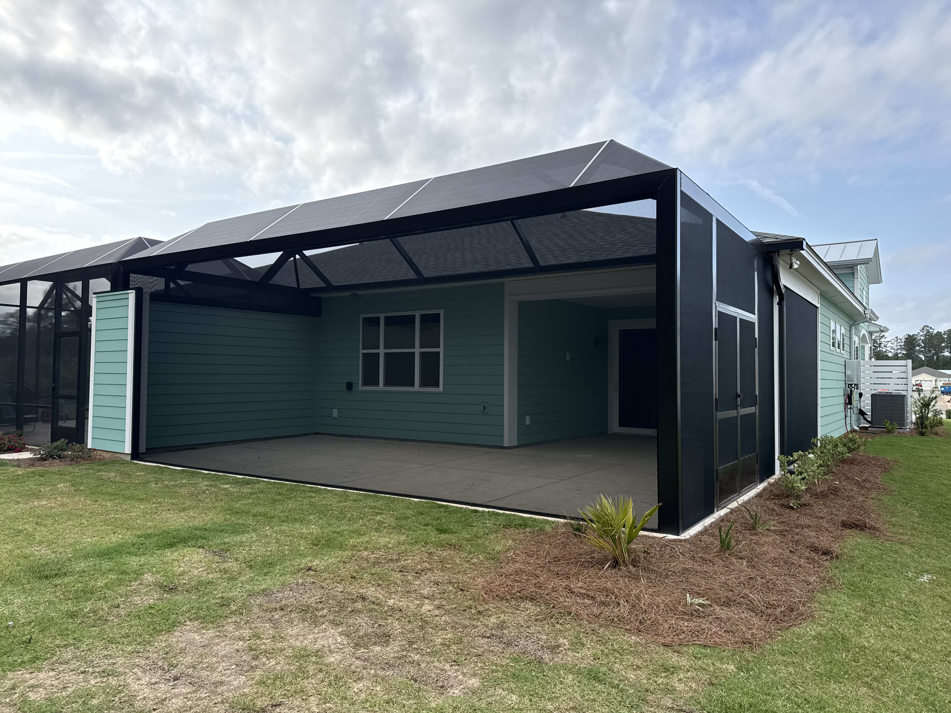 A black screened enclosure featuring green siding and a spacious interior in South Carolina.