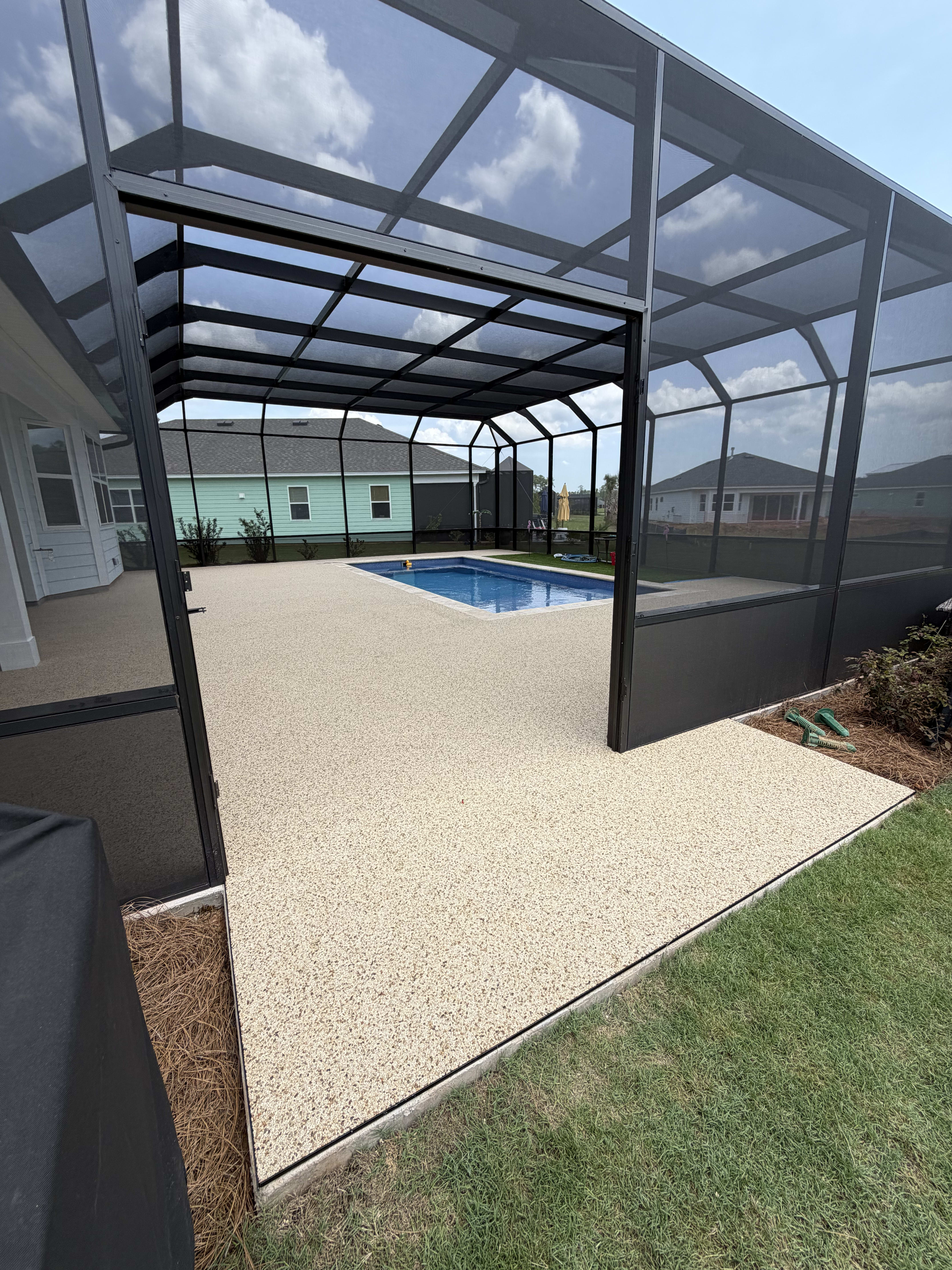 A textured pool deck surrounding a blue swimming pool within a screened enclosure in South Carolina.