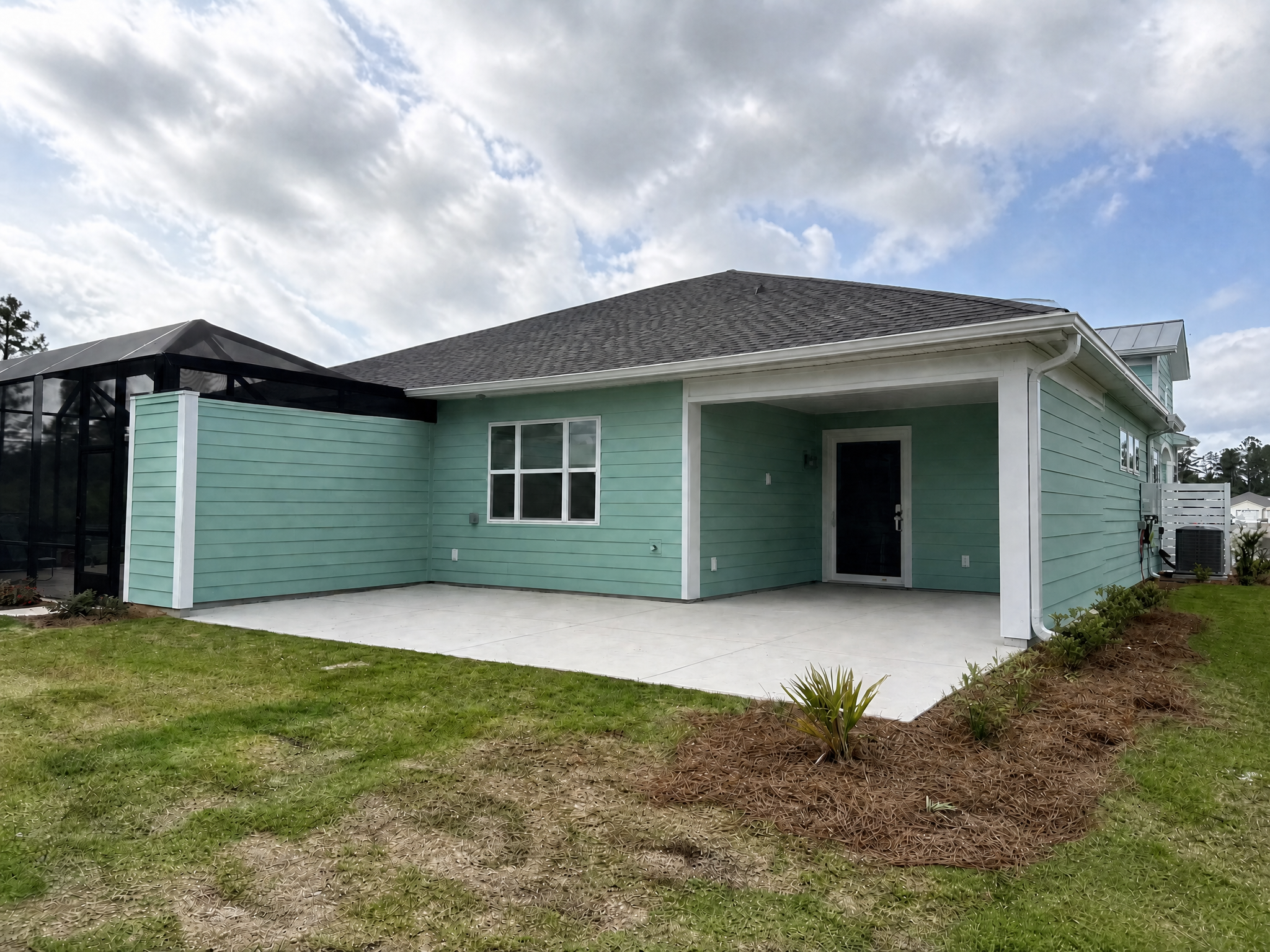 A newly installed concrete patio in front of a house with green siding in South Carolina.