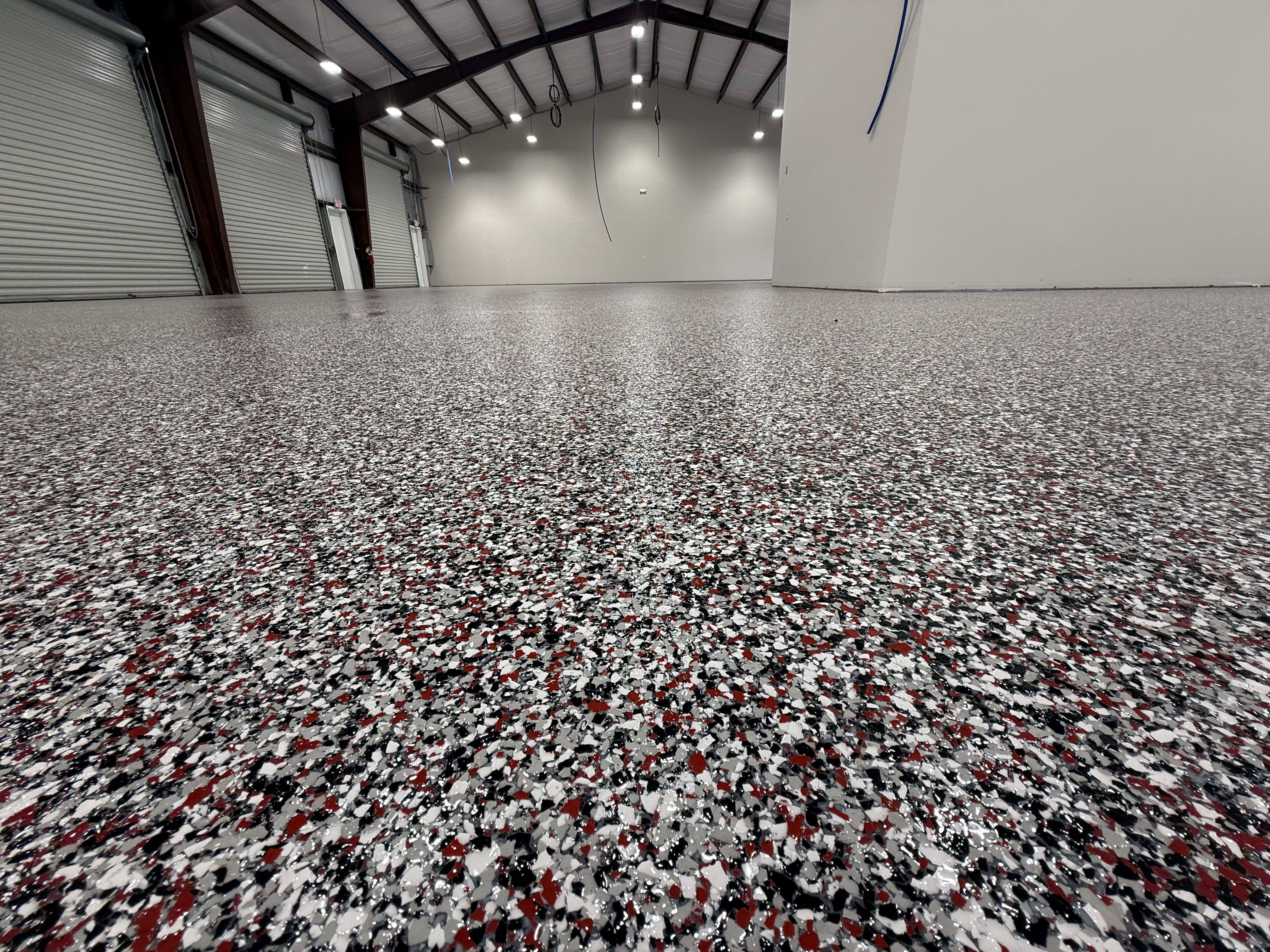 A close-up view of a newly installed epoxy floor with a speckled finish in a spacious area.
