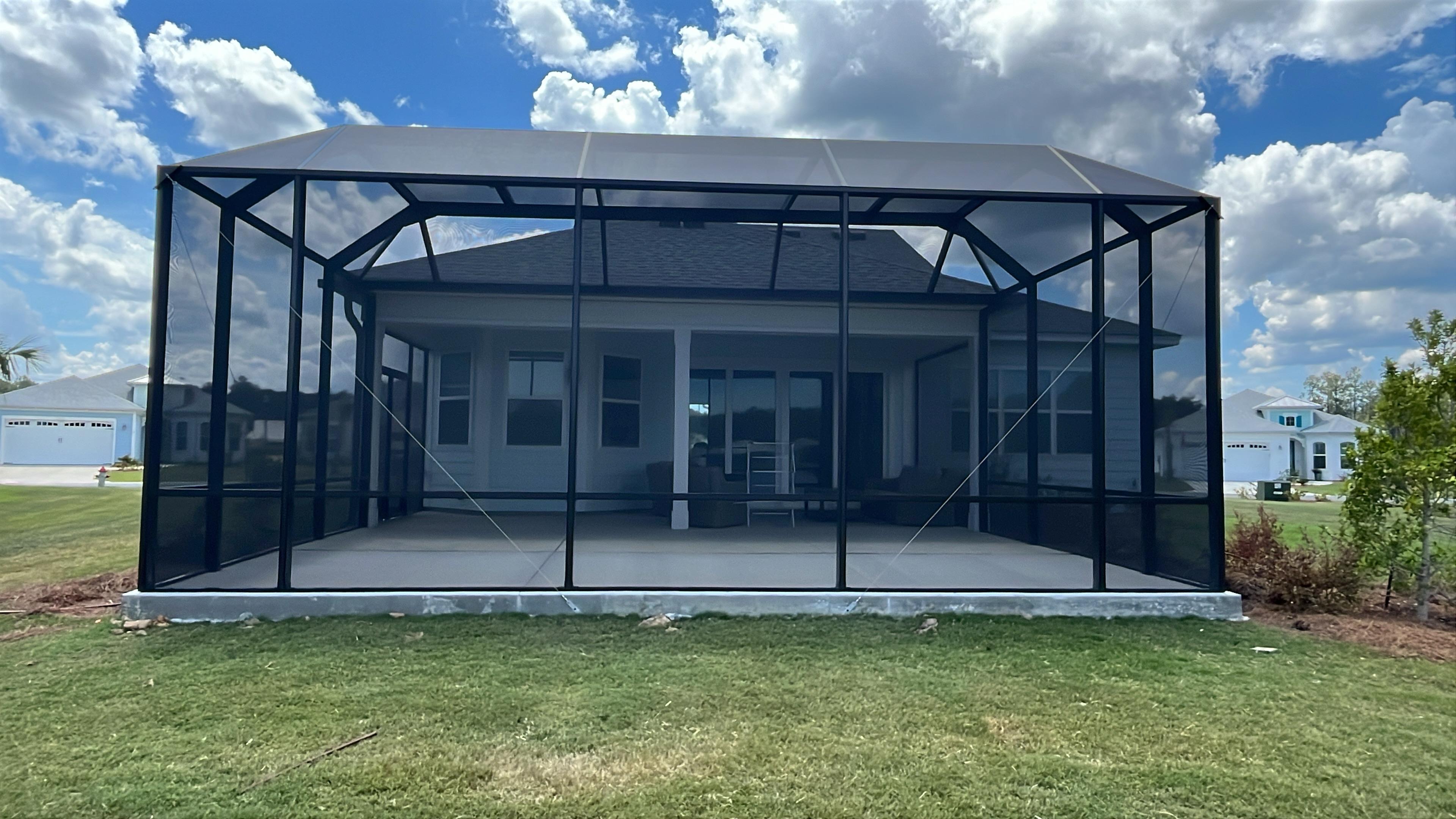 A black screened enclosure showcasing a white house with large windows and a grassy area in South Carolina.