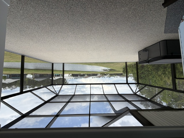A spacious screened enclosure featuring a view of a tranquil water body and grassy area in South Carolina.
