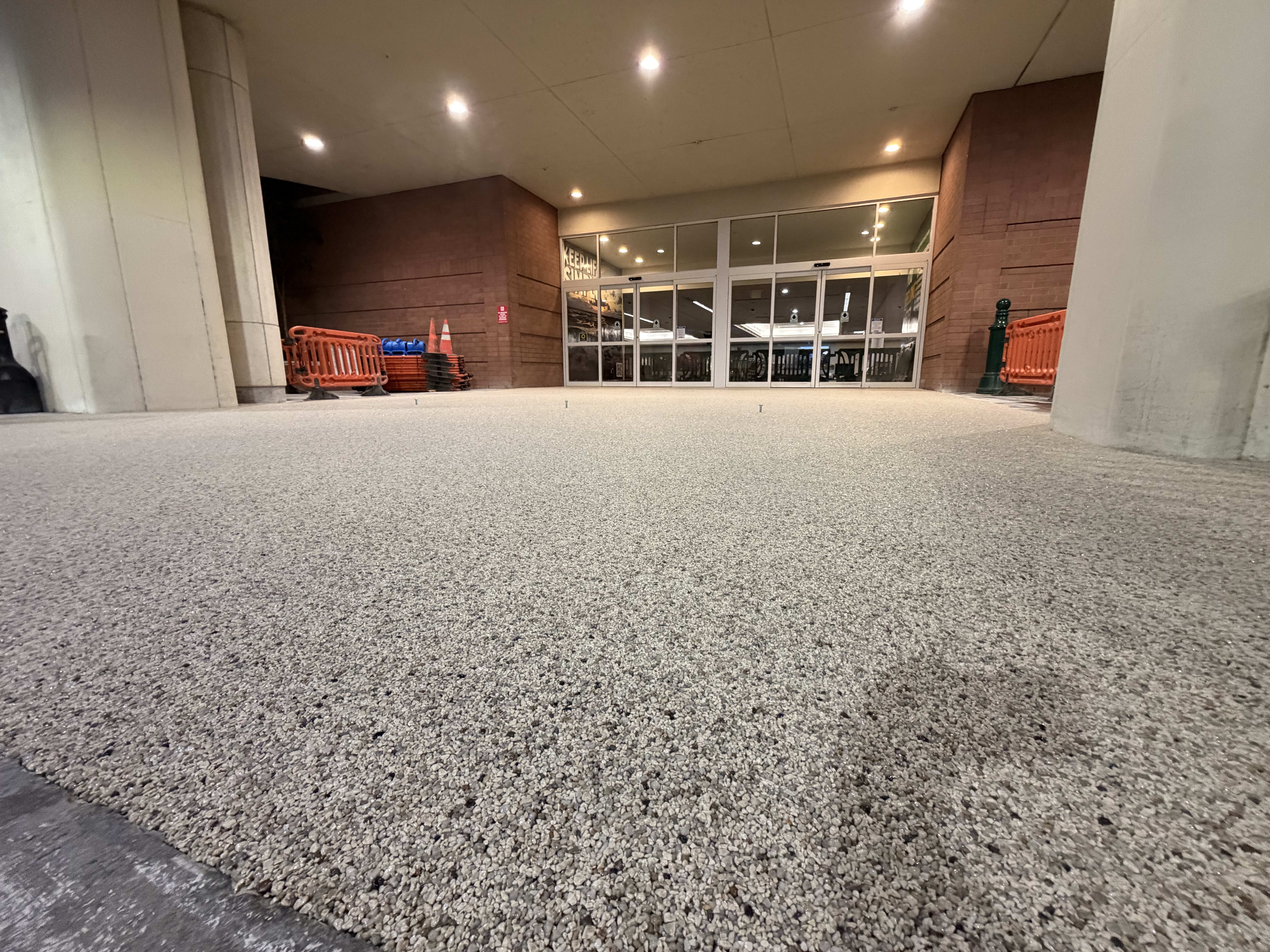 A close-up view of a smooth resin-bound stone entryway leading to a building entrance.