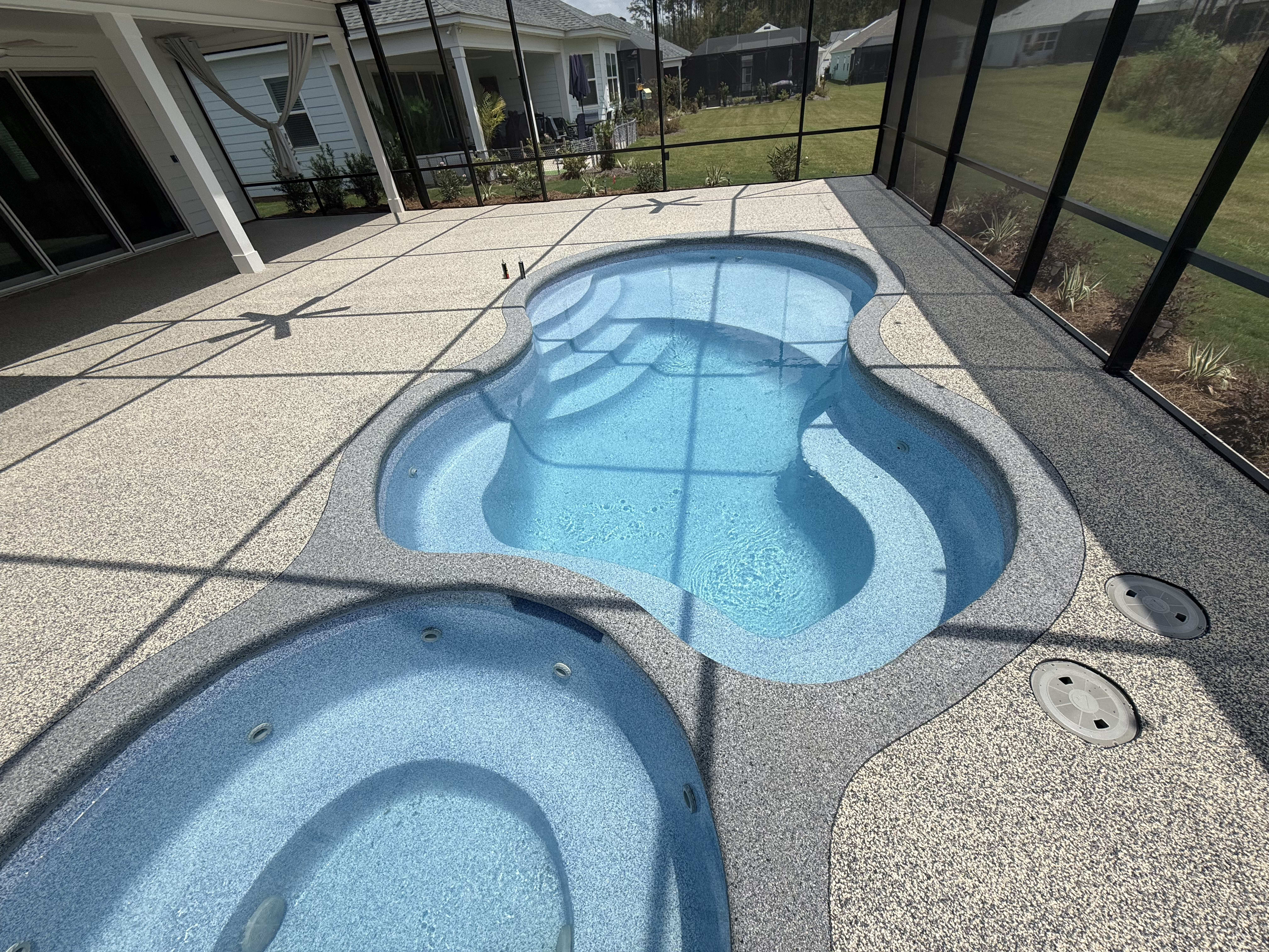 A beautifully designed screened pool enclosure featuring a sparkling blue pool in a coastal setting.