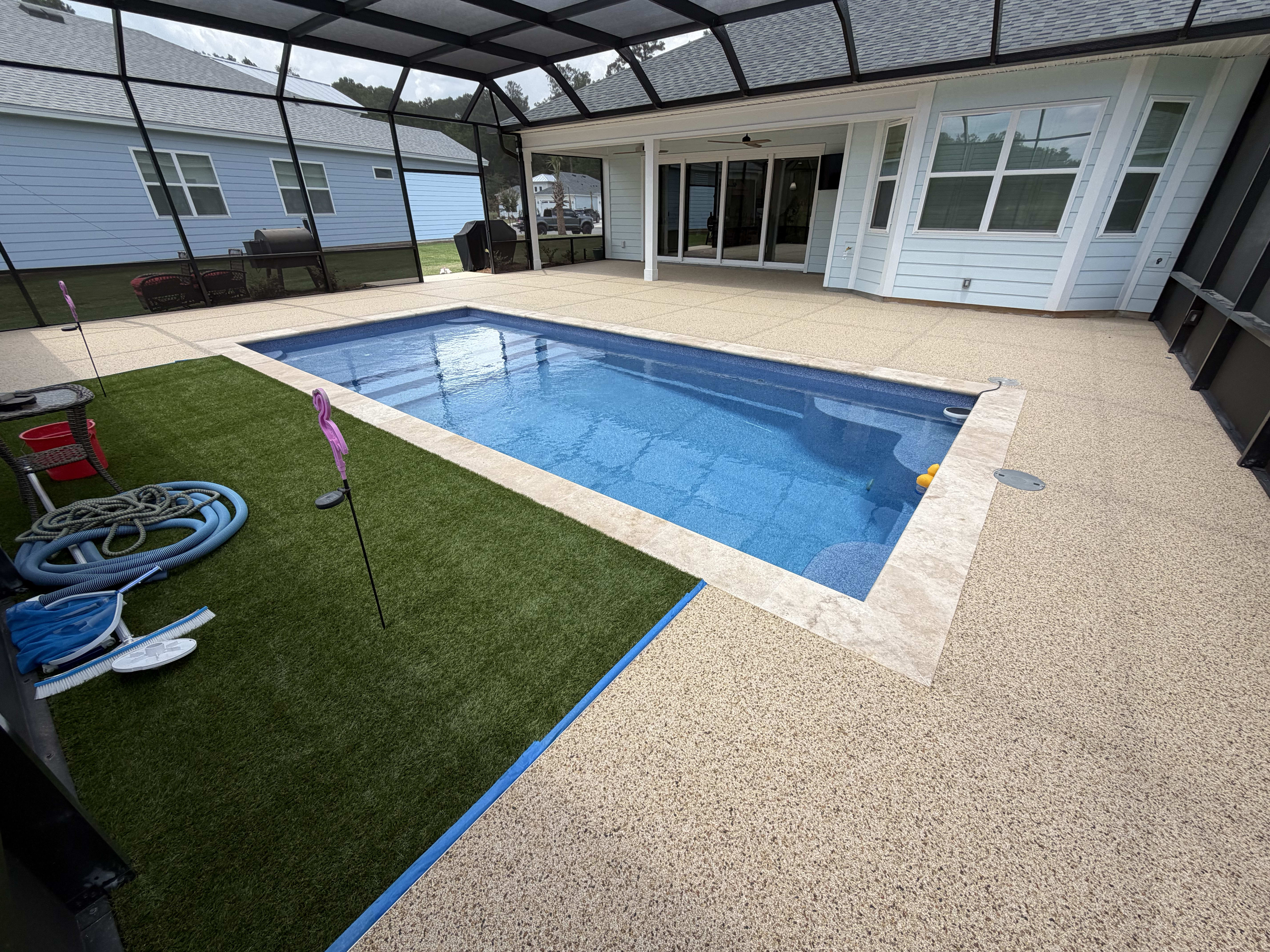 Textured pool deck with blue pool and surrounding grass