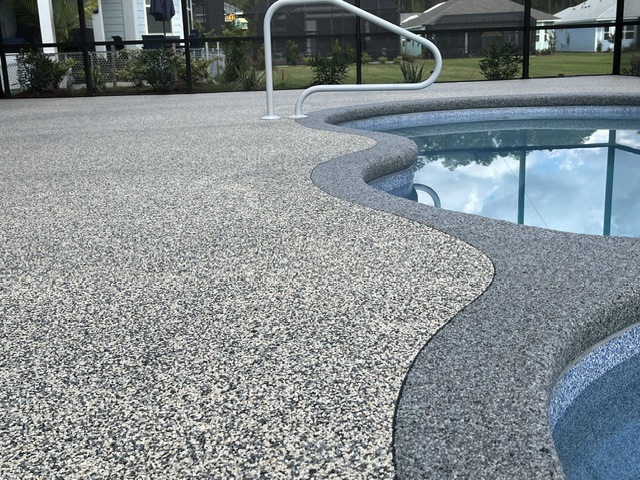 A textured resin-bound pool deck coating surrounding a blue pool with a smooth edge.