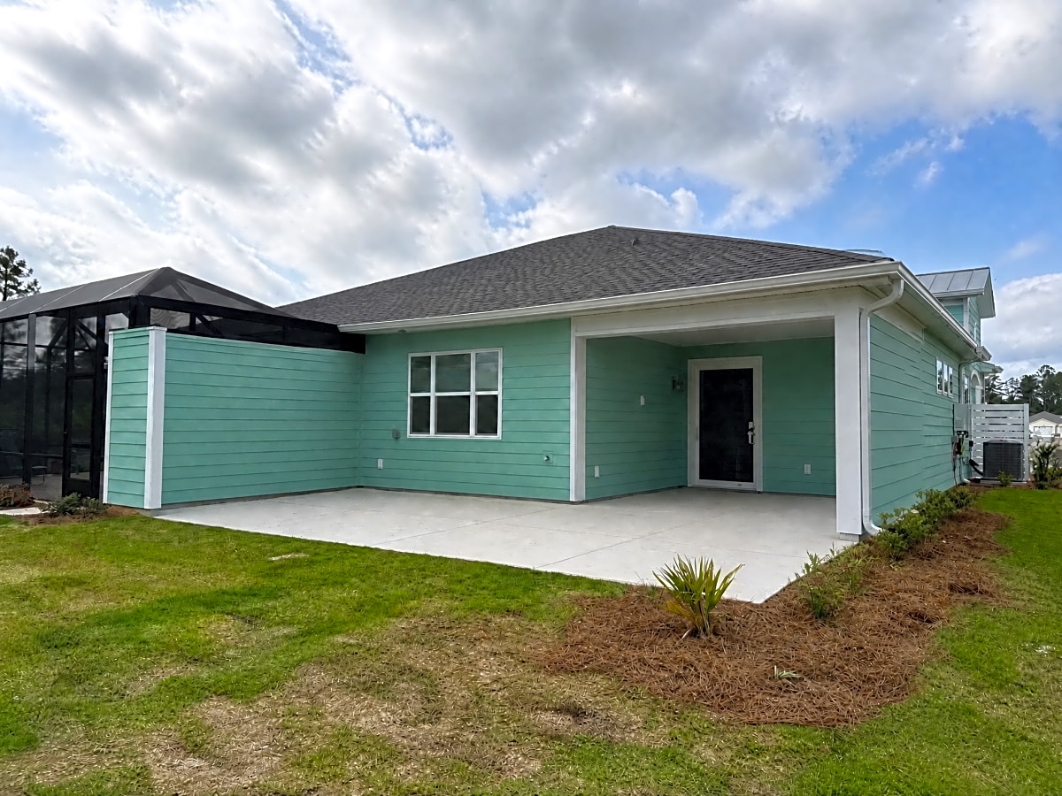 A newly installed concrete patio in front of a house with green siding in South Carolina.