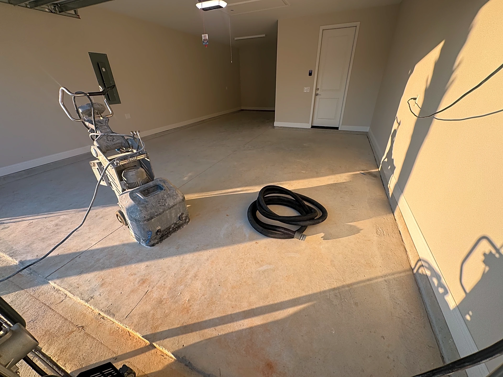 A garage floor before coating, showing bare concrete and preparation work.