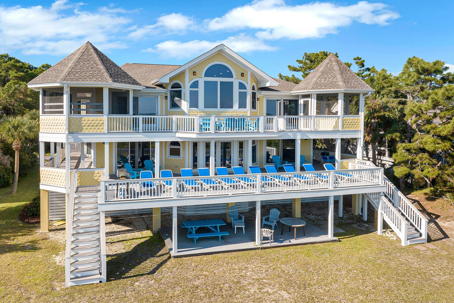Rear view of home showing upper deck, screen rooms, lower deck and patio