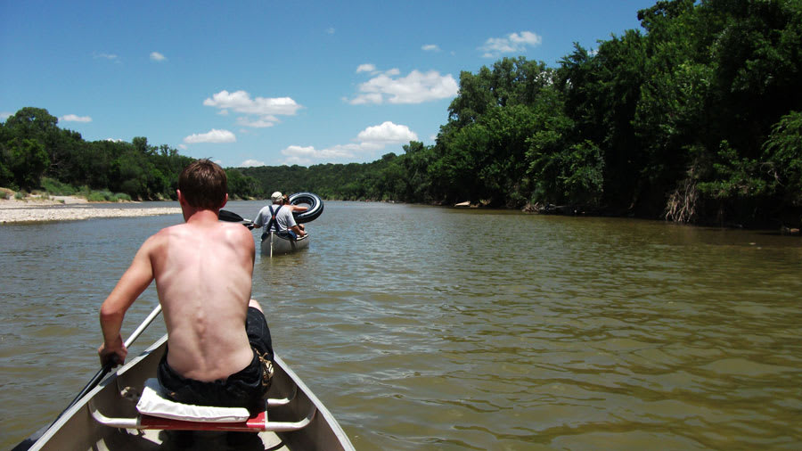 Man canoeing on river with sunburns on the shoulders