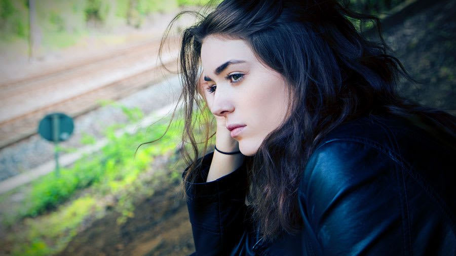 pretty girl with black hair dressed in black looking sad and thinking to herself