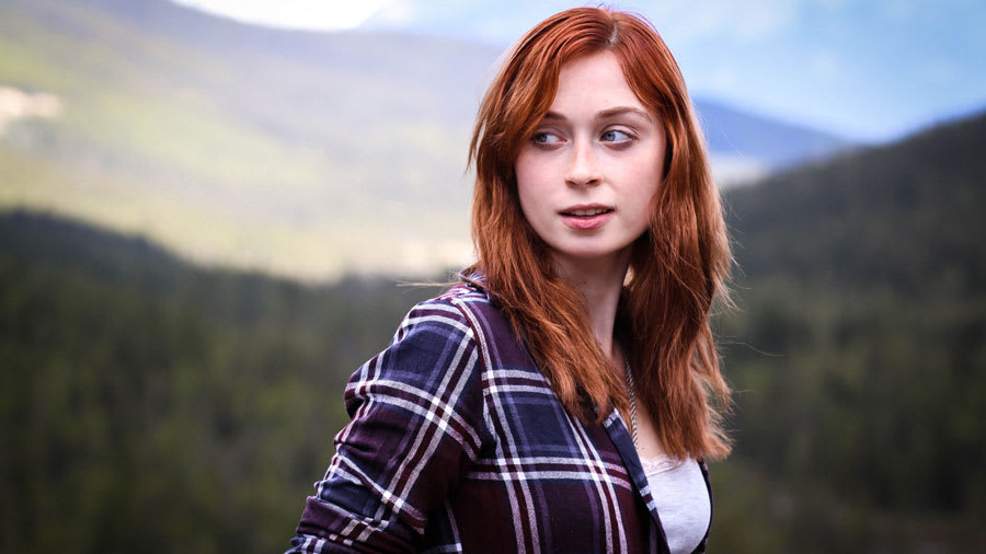 Pale-skinned red-haired woman with flushed red face wearing white shirt and dark blue flannel looking to the side