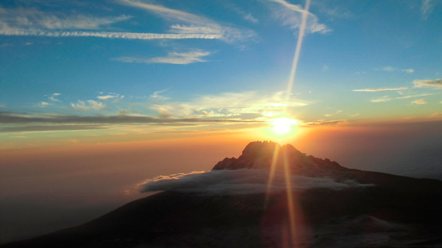 Sunrise over the horizon above mountains and clouds
