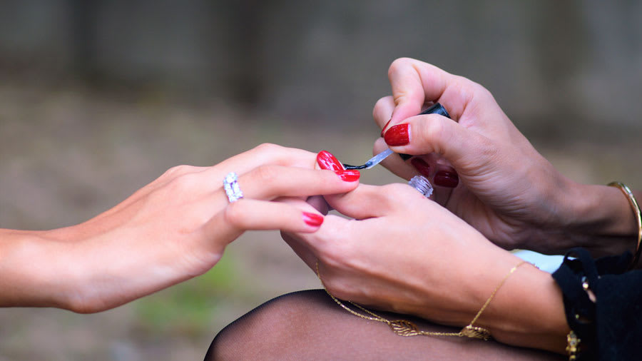Red nail polish being applied during a manicure