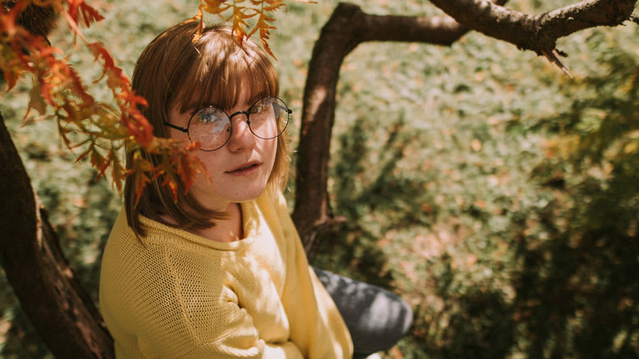woman with acne sitting outside next to tree