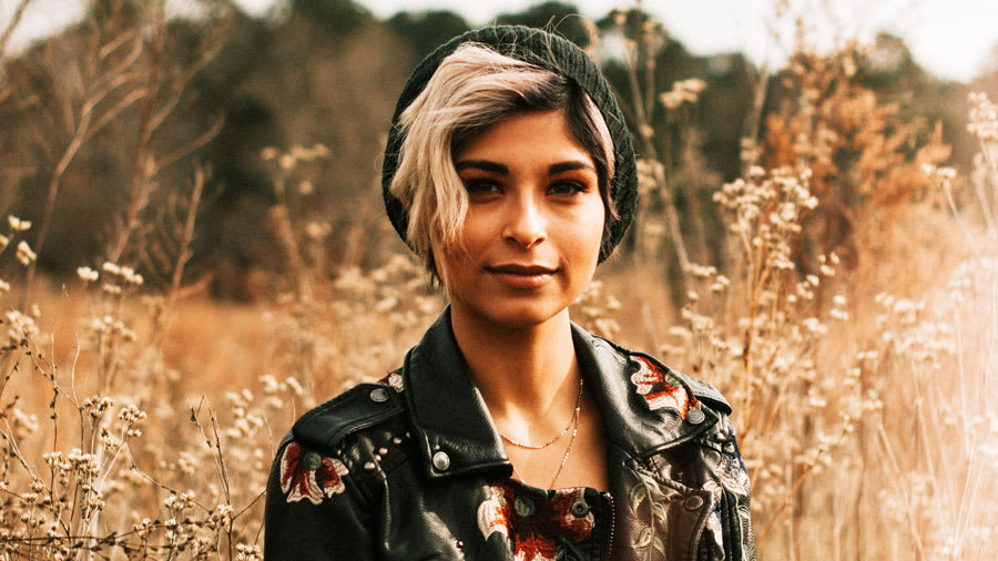 clear-skinned latina woman standing in field