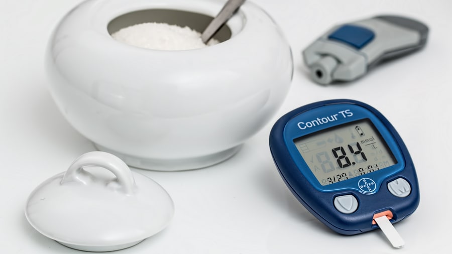 Sugar in white container with spoon next to stopwatch