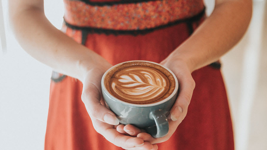 Woman wearing red dress holding cup of coffee