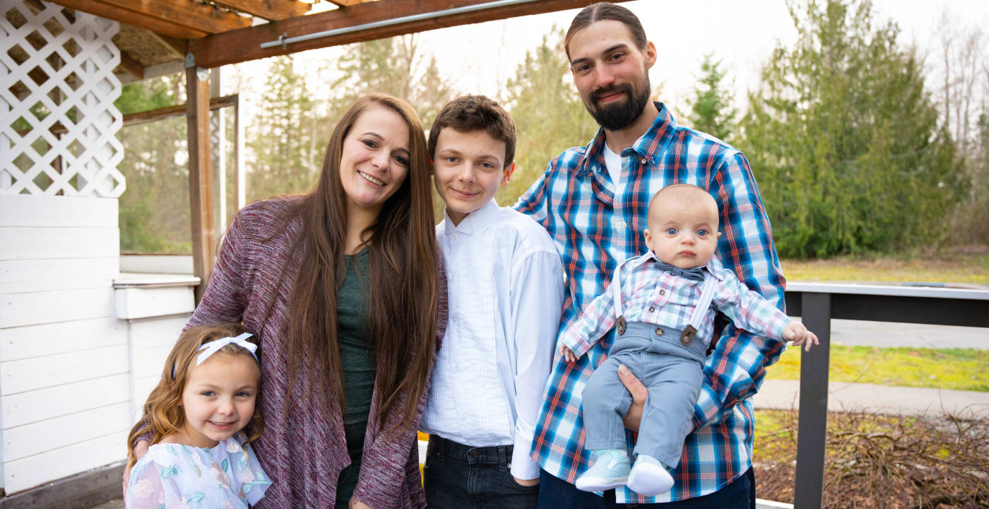 Mom, dad and three children pose on a deck outdoors