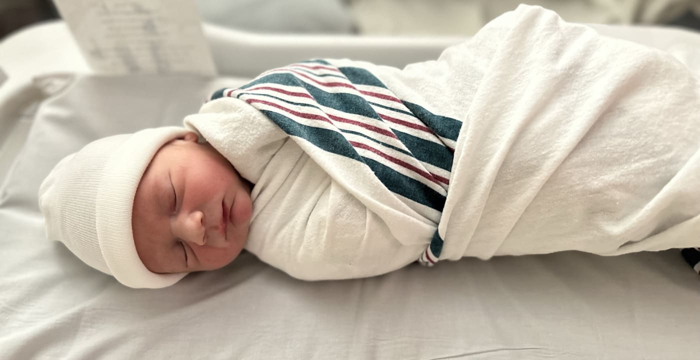 Newborn baby swaddled in hospital blanket.