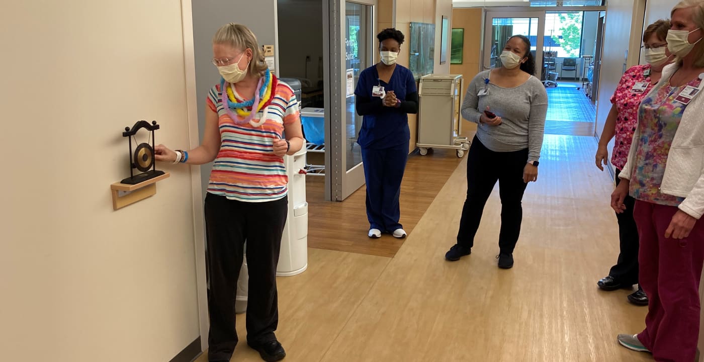 Woman ringing a gong in celebration of beating cancer.