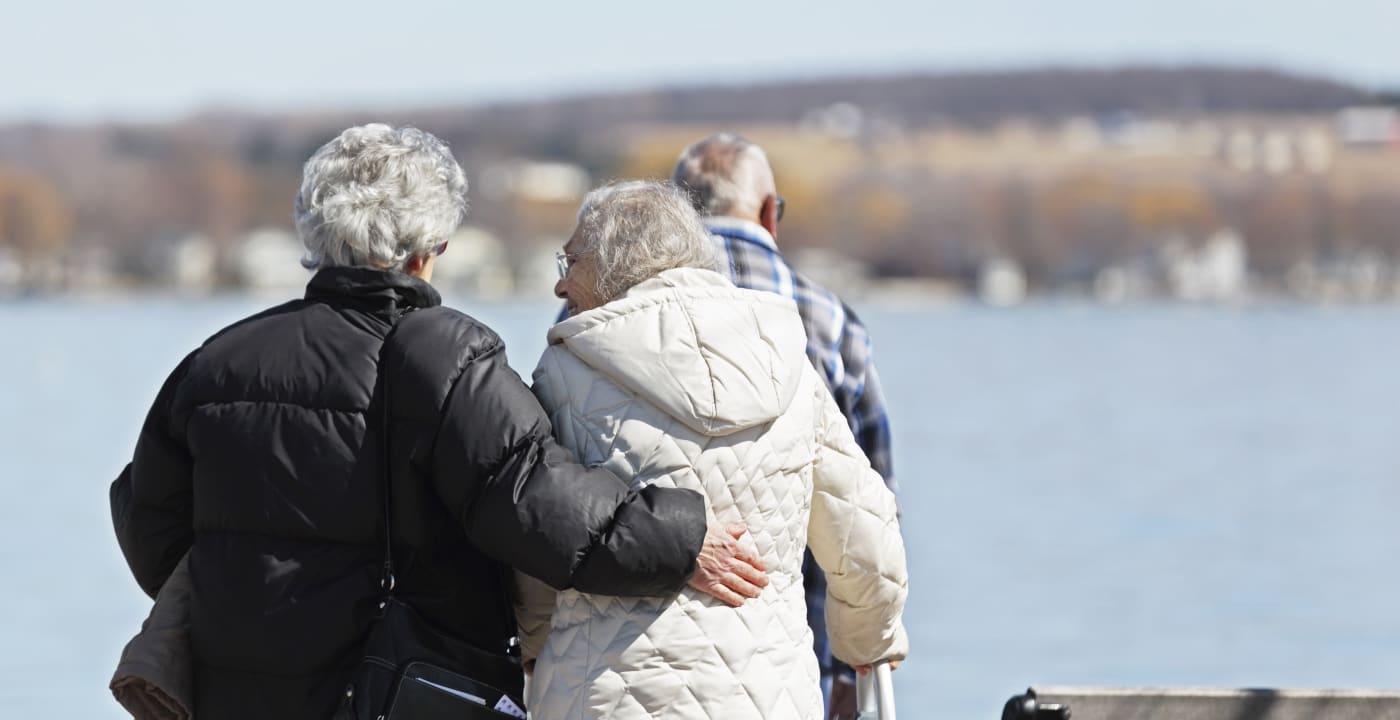 Two older women and one older man walking alongside a body of water