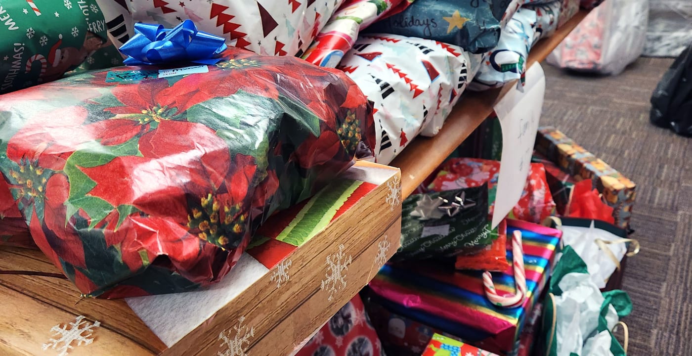 Piles of Christmas gifts stacked on a table in a conference room