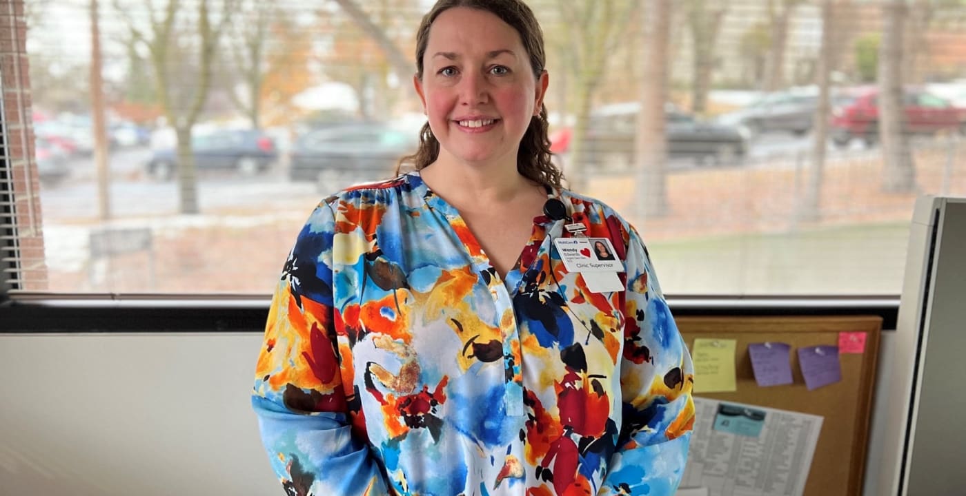 Woman stands in front of a window smiling at the camera