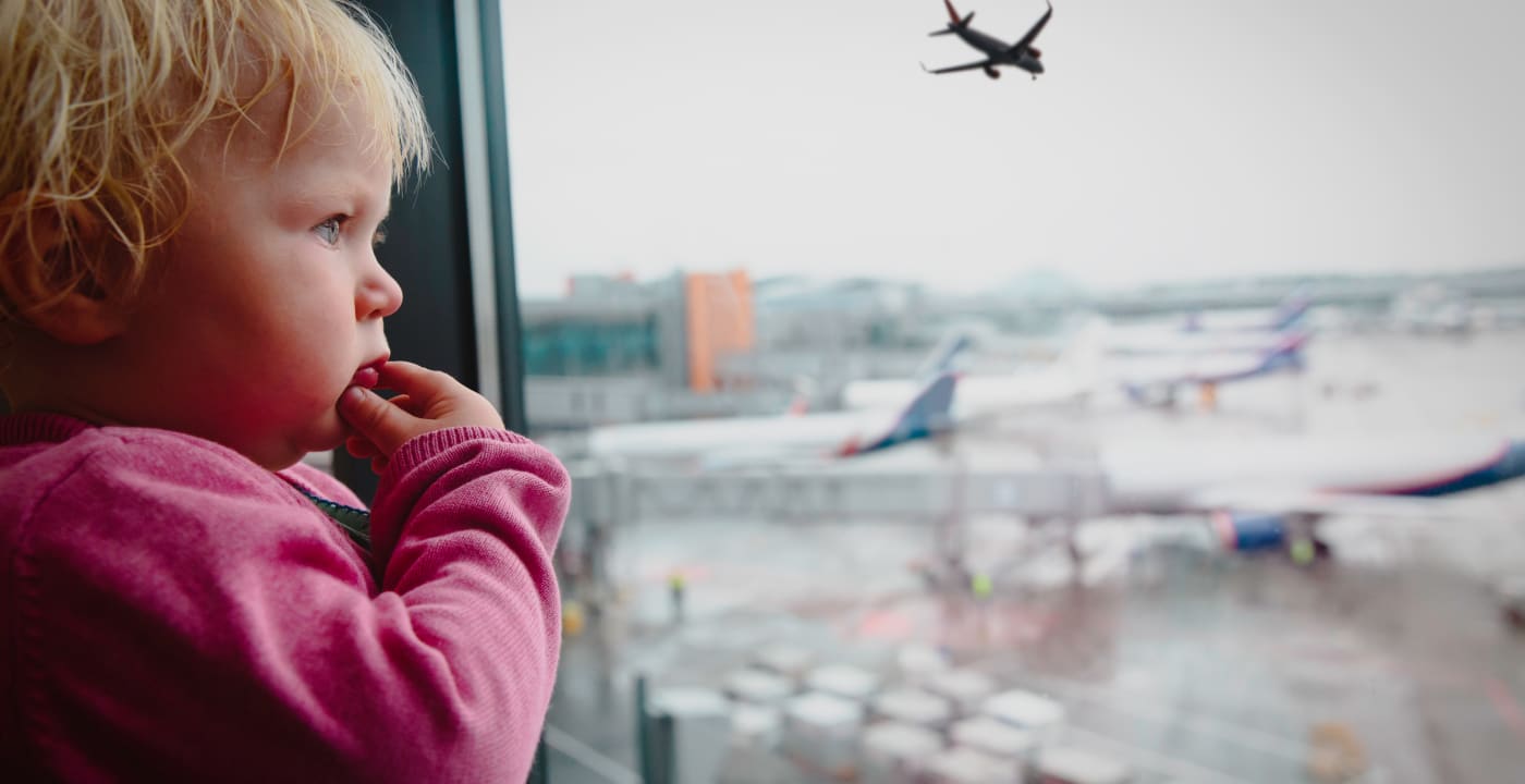 Child at airport looking out the window at planes