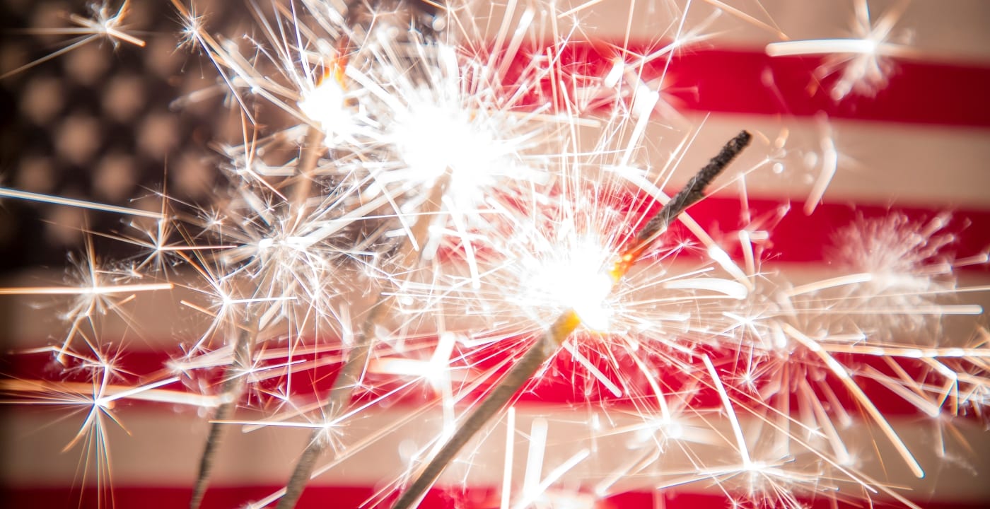 Lit sparklers held in front of the U.S. flag