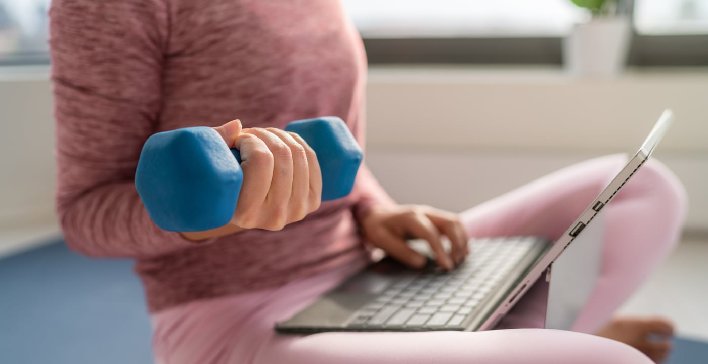 Woman lifting weight and looking on a computer