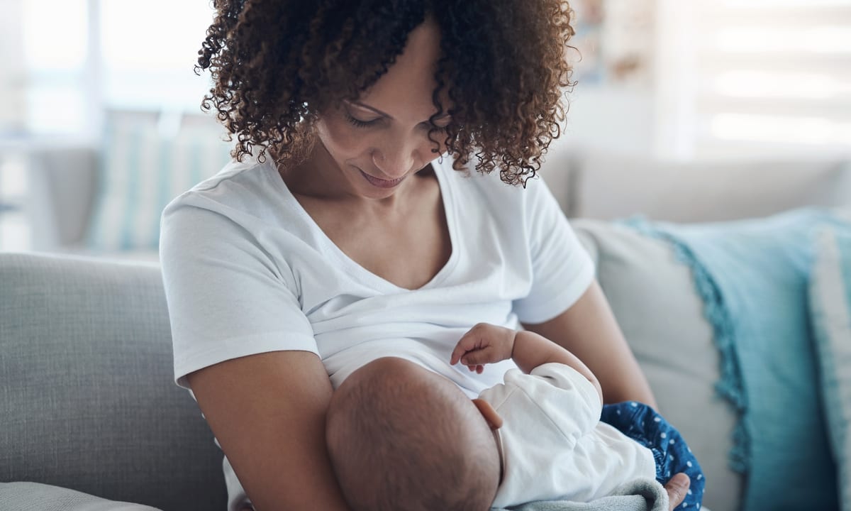 Women with dark curly hair breastfeeding an infant