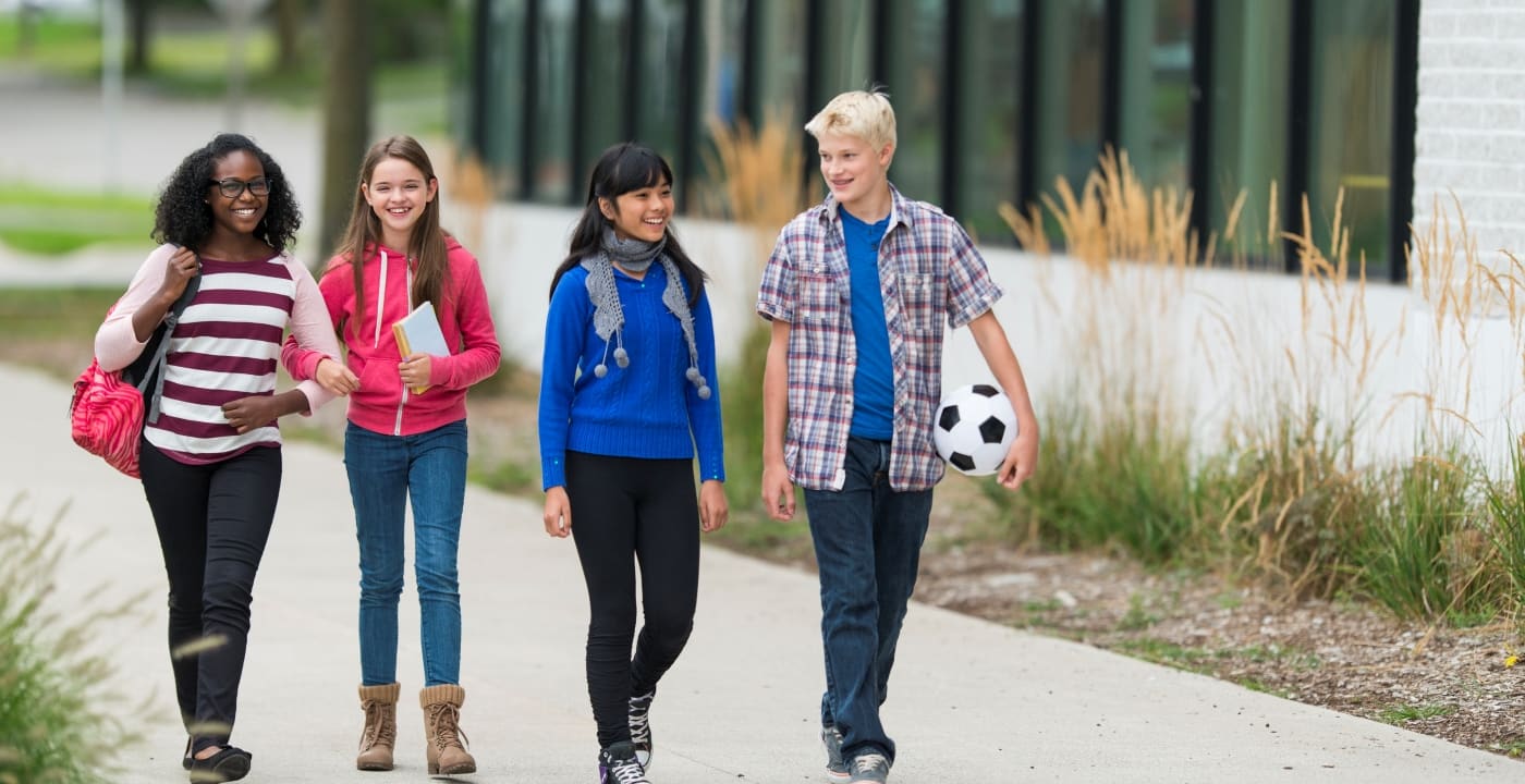 A group of preteens walk down a sidewalk