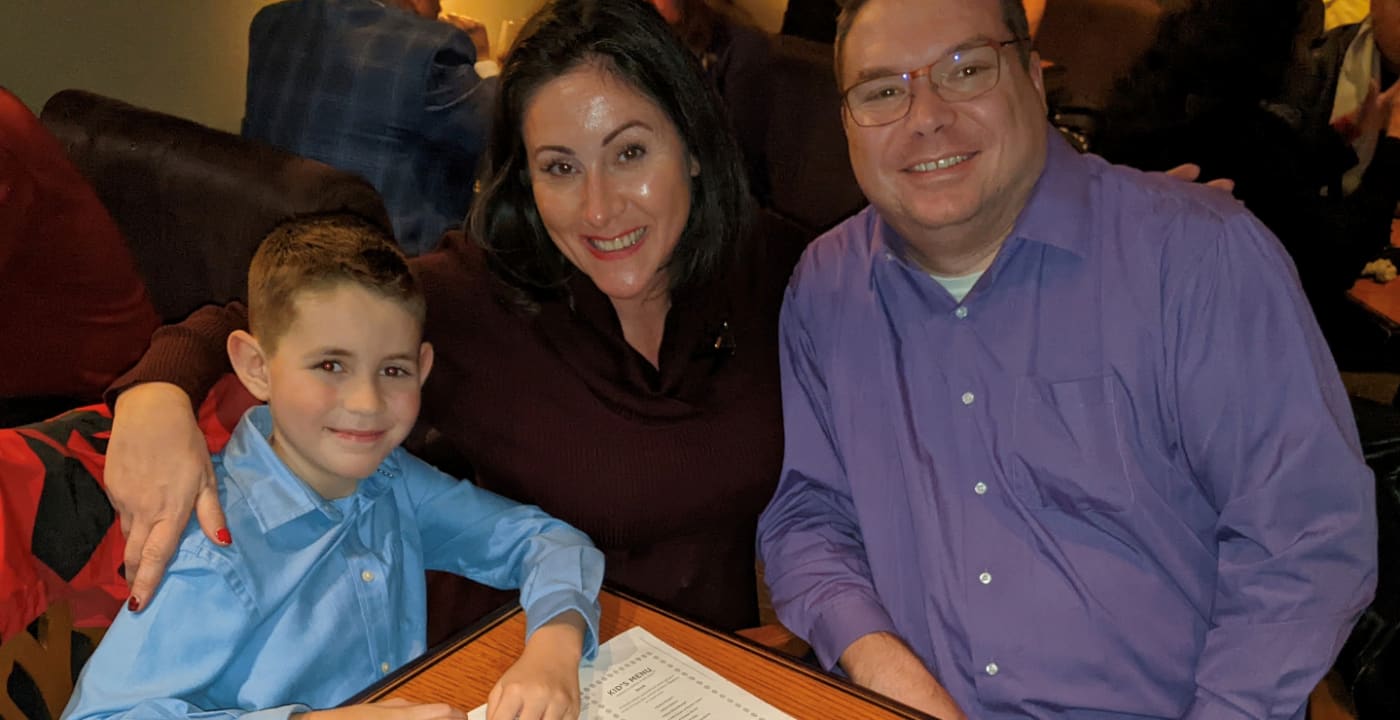 Mom, dad and young son pose for the camera at a table