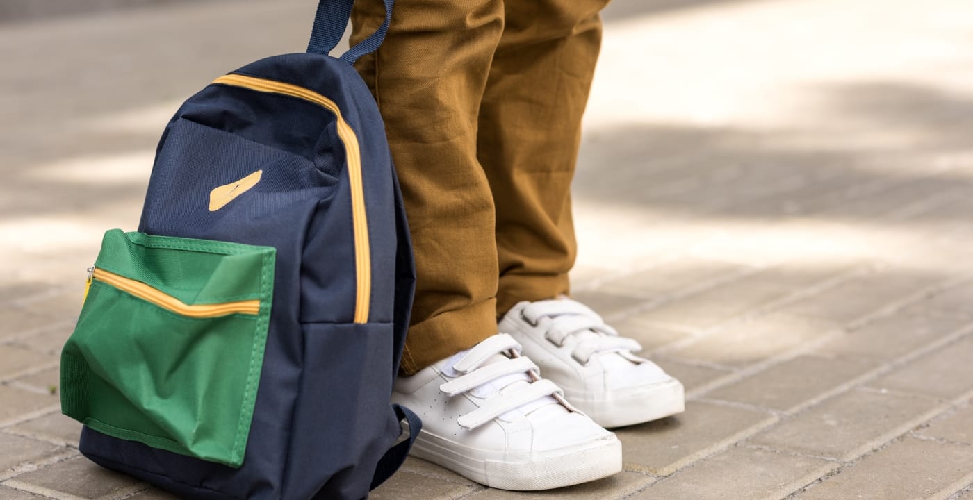 Student standing with backpack on sidewalk