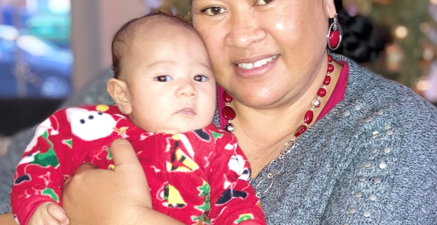 Woman holding her baby in front of a Christmas tree