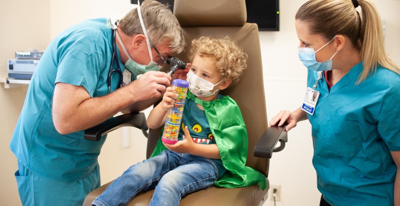 Child having his ears checked by medical professionals