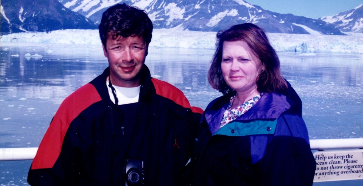 Older photo of a couple posing by a mountain.