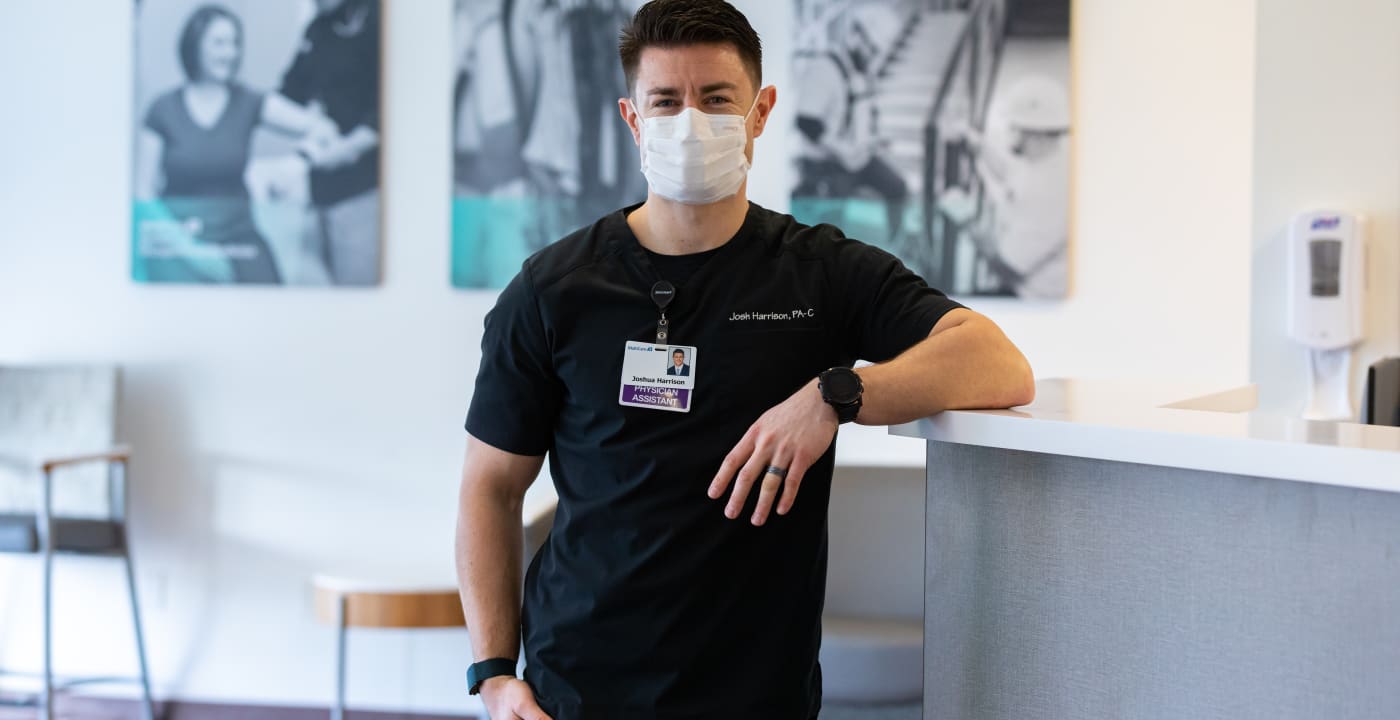 Masked medical professional leaning against the counter