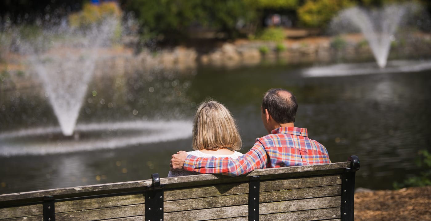 Older couple sitting on bench looking at a fountain